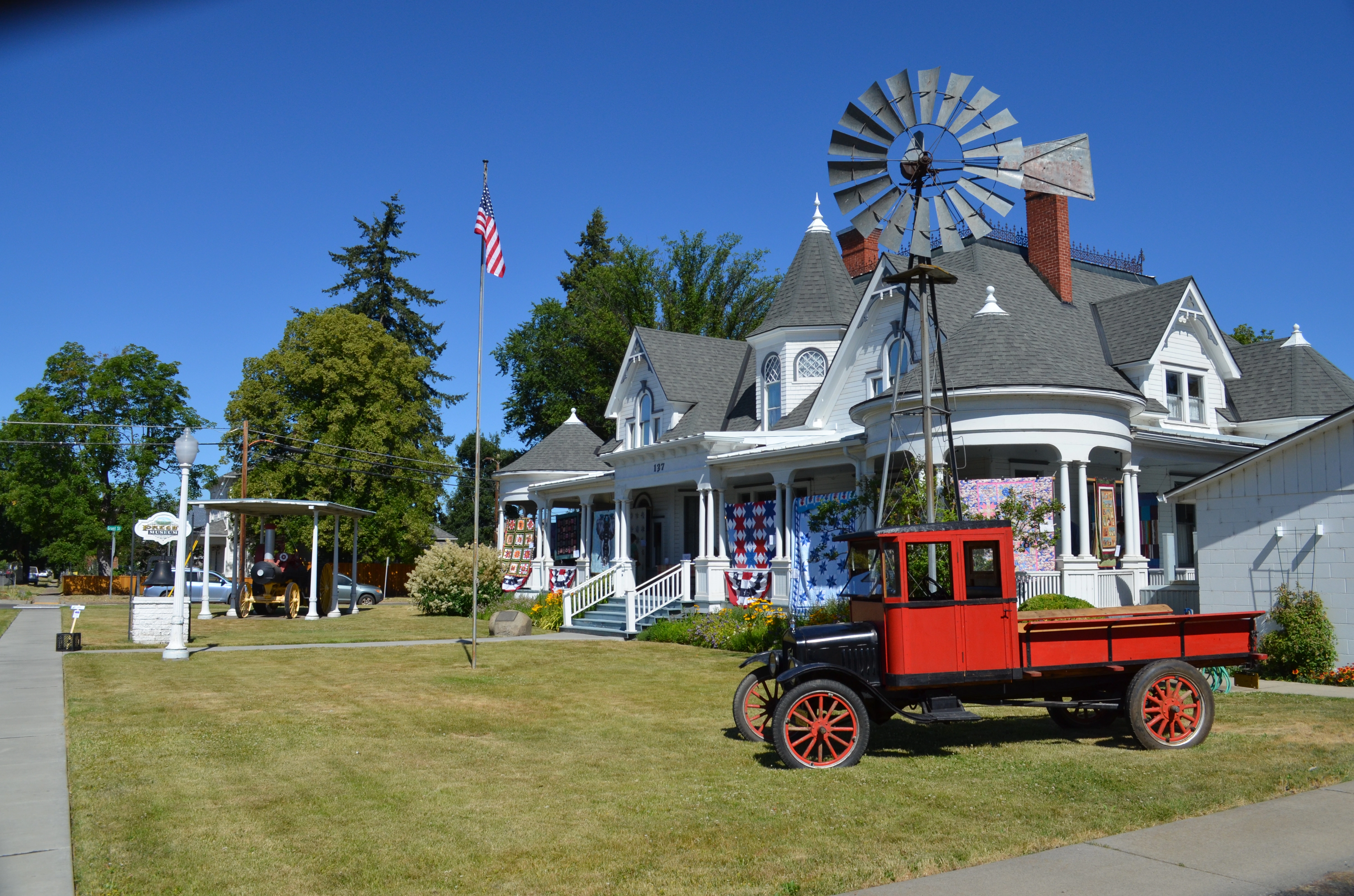 A red antique car parked in front of the Presby Mansion