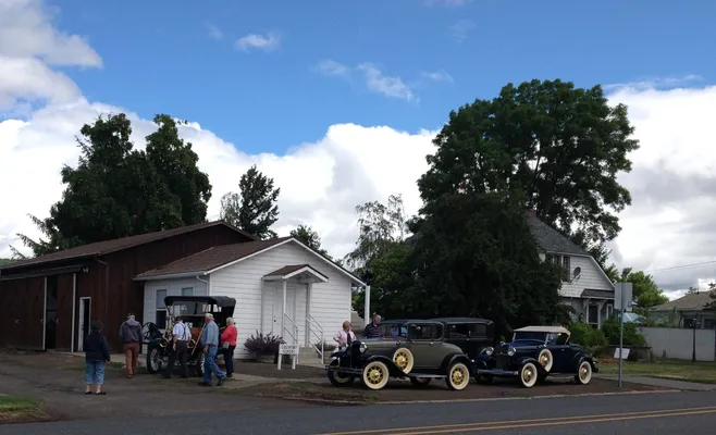 Antique cars parked in front of the schoolhouse