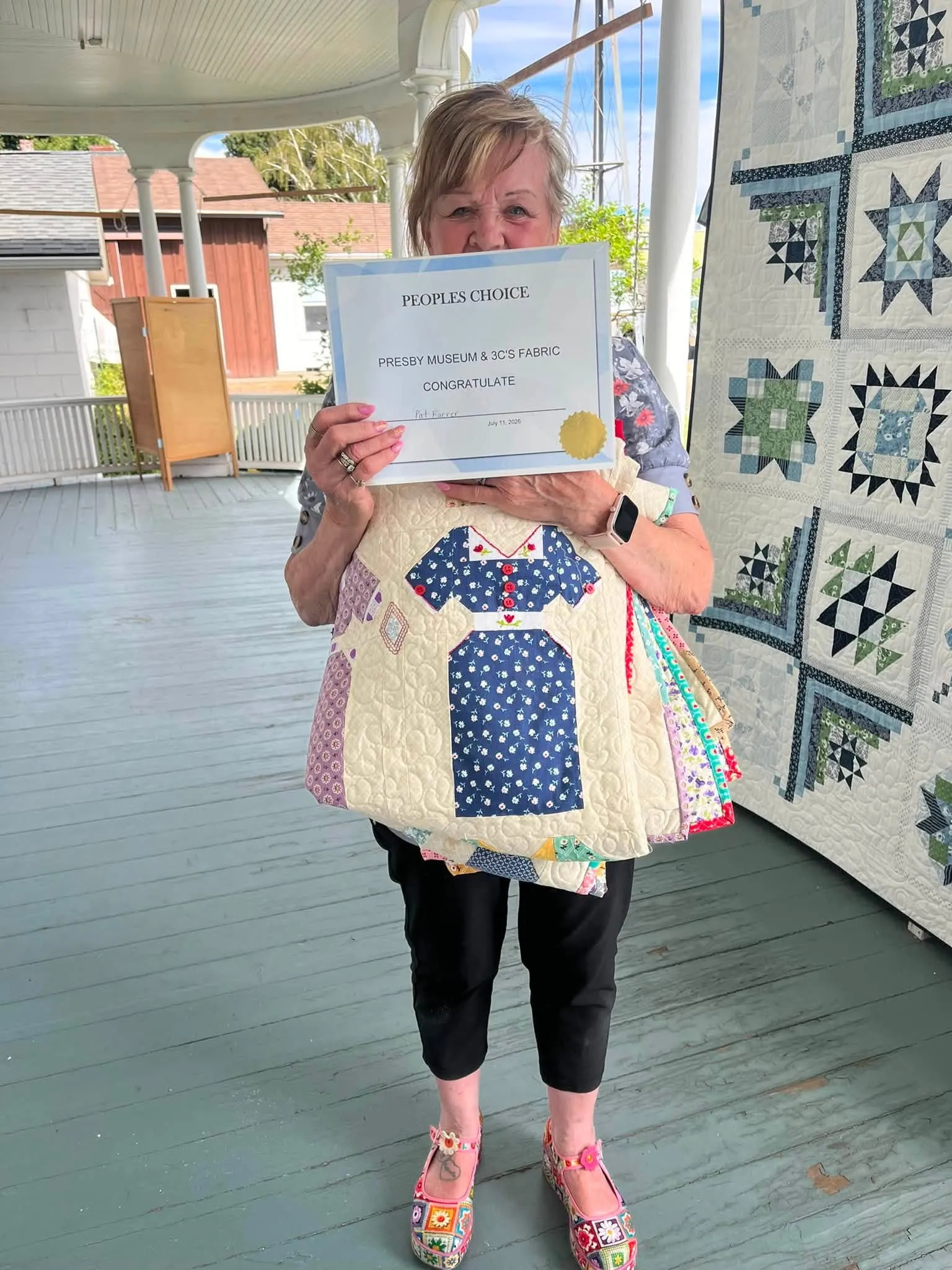 Quilter holding the People's Choice award on the museum porch