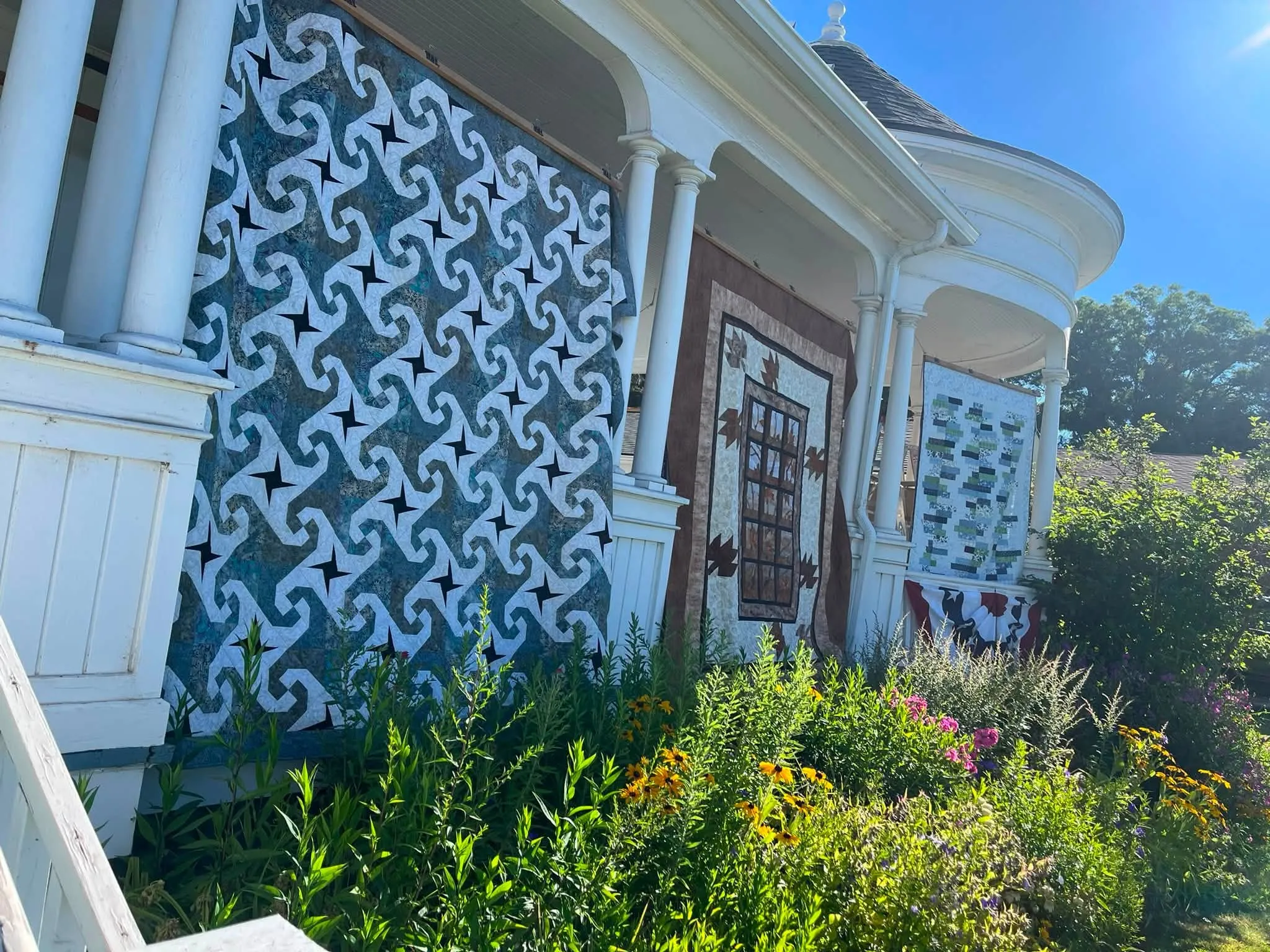 Navy and cream ocean-waves quilt on the porch above a wildflower garden